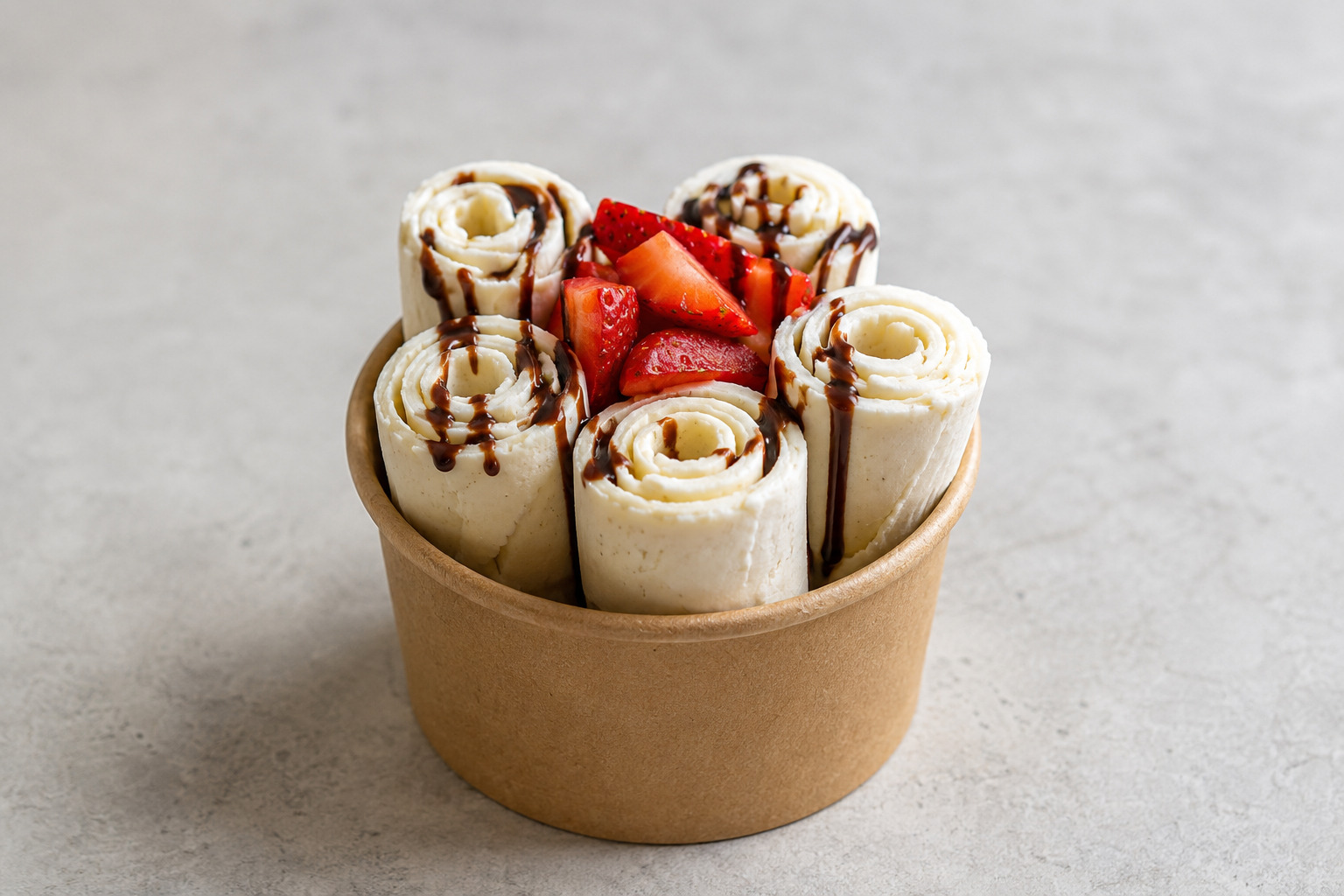 Vanilla rolled ice cream recipe served as five rolls with strawberries and a light chocolate drizzle